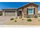 Charming home with stone accents, a two-car garage, desert landscaping, and a paved driveway at 27366 W Escuda Dr, Buckeye, AZ 85396