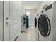 Bright laundry room with white washer and dryer, shelving unit, and door to the outside at 27366 W Escuda Dr, Buckeye, AZ 85396