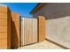 Side yard view showing a wood gate with metal hardware in between cinder block columns and a pea gravel walking surface at 27366 W Escuda Dr, Buckeye, AZ 85396