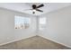 Empty bedroom featuring neutral walls, carpeted floor, two windows, and a ceiling fan at 38179 W La Paz St, Maricopa, AZ 85138