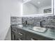 Close-up of a bathroom with double glass vessel sinks and a gray stone backsplash creating a stylish focal point at 3915 E Hillery Dr, Phoenix, AZ 85032