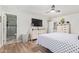 Bedroom with wood-look floors, TV, bathroom access, and white storage cabinet with sliding doors at 4857 N Granite Reef Rd, Scottsdale, AZ 85251