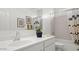 Bright bathroom featuring a white single sink vanity, decorative art, and shower with patterned curtain at 4939 S 105Th Dr, Tolleson, AZ 85353