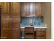 Built-in kitchen desk with wood cabinets, granite counters, tile backsplash and an upholstered chair at 5450 N Globe Dr, Eloy, AZ 85131