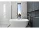 Bathroom with a modern tub, a large window, and stylish gray and speckled tile work at 6338 N 10Th Dr, Phoenix, AZ 85013