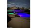 Night view of a backyard pool illuminated with colorful LED lighting and rock features at 6458 W Adobe Dr, Glendale, AZ 85308