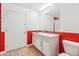 Stylish bathroom with red accent tiles, vanity with white cabinets, and wood-look flooring at 7662 W Artemisa Ave, Peoria, AZ 85383