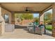 Inviting covered patio features comfortable seating, fan, and a view of the well-maintained backyard at 7662 W Artemisa Ave, Peoria, AZ 85383