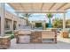 Well-equipped outdoor kitchen with a built-in grill, storage, and stone accents, perfect for outdoor entertaining by the pool at 7662 W Artemisa Ave, Peoria, AZ 85383