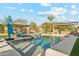 Stunning backyard pool featuring a baja shelf, travertine decking, and outdoor kitchen with a covered dining area at 7662 W Artemisa Ave, Peoria, AZ 85383