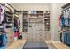 Large walk-in closet with custom shelving and storage solutions with centered ottoman at 7662 W Artemisa Ave, Peoria, AZ 85383