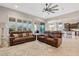 Living room with tile flooring, ceiling fan, brown leather sofas, and windows that provide ample natural light at 7717 W Noble Prairie Way, Florence, AZ 85132