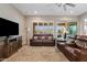 The living room features a brown leather sofa, tile flooring, neutral paint, and windows with plantation shutters at 7717 W Noble Prairie Way, Florence, AZ 85132