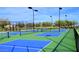 Multiple bright blue and green pickleball courts under a sunny sky, surrounded by fencing and landscaping at 7717 W Noble Prairie Way, Florence, AZ 85132