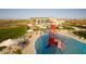 Aerial view of the community pool showcasing water slides, splash pads, lounge chairs and beautiful lush green landscape at 7946 W Sonoma Way, Florence, AZ 85132