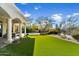 Expansive backyard featuring manicured lawn, covered patio, and stone fireplace with lush landscaping at 9290 E Thompson Peak Pkwy # 142, Scottsdale, AZ 85255