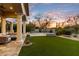 Lush backyard showcasing manicured lawn, outdoor fireplace, seating area, and desert landscaping at 9290 E Thompson Peak Pkwy # 142, Scottsdale, AZ 85255