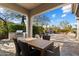 Covered outdoor dining area with a built-in grill, stone patio, and lush backyard landscaping at 9290 E Thompson Peak Pkwy # 142, Scottsdale, AZ 85255