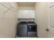 Functional laundry room features modern appliances, white cabinets, and a wire shelf for storage at 13220 N 99Th Pl, Scottsdale, AZ 85260