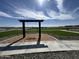 Modern metal swing set and park bench overlook large green field with sprinklers in operation at 15668 W Deanne Dr, Waddell, AZ 85355