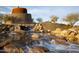 Water feature flowing over rocks and boulders, with a stone tower in the background at 17857 W Desert View Ln, Goodyear, AZ 85338