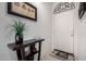 Inviting entryway with decorative table, plant, artwork, and decorative wrought iron piece above a bright white door at 18644 N Desert Willow Dr, Maricopa, AZ 85138