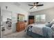 Well-lit main bedroom featuring wooden furniture, ceiling fan and an ensuite bathroom at 18644 N Desert Willow Dr, Maricopa, AZ 85138