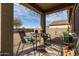 Cozy covered patio featuring outdoor seating, string lights, and decorative accents overlooking a low-maintenance backyard at 18644 N Desert Willow Dr, Maricopa, AZ 85138