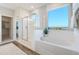 Bright bathroom featuring a soaking tub, walk-in shower, and large window with views, creating a spa-like oasis at 19201 W Missouri Ave, Litchfield Park, AZ 85340