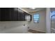 Laundry room features overhead cabinets, a window, tile flooring, and washer/dryer hookups at 19201 W Missouri Ave, Litchfield Park, AZ 85340
