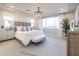 Bright main bedroom featuring a tray ceiling, elegant chandelier, large window, and a stylish chevron rug at 19201 W Missouri Ave, Litchfield Park, AZ 85340