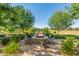 Enjoy the community firepit featuring a stone surround, Adirondack chairs, and mature landscaping at 19912 E Natalie Way, Queen Creek, AZ 85142