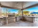 Well-equipped outdoor kitchen with stainless steel grill, countertop seating, and view of the pool at 19912 E Natalie Way, Queen Creek, AZ 85142