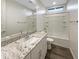 Bright bathroom with a granite countertop, a bathtub with white tile, and modern fixtures at 2061 W Burnside Trl, Phoenix, AZ 85085