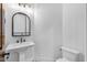 Elegant bathroom featuring a pedestal sink, modern lighting, toilet, and ceramic tile floor at 21442 E Excelsior Ave, Queen Creek, AZ 85142