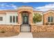 Close-up of the entrance to the house featuring stone accents, an iron gate, and lush landscaping at 21442 E Excelsior Ave, Queen Creek, AZ 85142