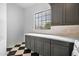 Laundry room with gray cabinets, white countertops and black and white tile floors at 21442 E Excelsior Ave, Queen Creek, AZ 85142