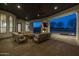 Outdoor living area featuring a stone fireplace, TV, and comfortable seating overlooking the pool at 21442 E Excelsior Ave, Queen Creek, AZ 85142