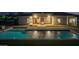 Backyard view with a pool reflecting the lights of the home and a stone fireplace at 21442 E Excelsior Ave, Queen Creek, AZ 85142