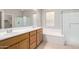 Bright bathroom featuring double sinks, a tub, and a separate glass-enclosed shower at 227 E Carob Dr, Chandler, AZ 85286