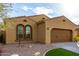 Home exterior featuring arched windows, desert landscaping, and a two-car garage at 227 E Carob Dr, Chandler, AZ 85286