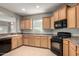 Spacious kitchen with light wood cabinetry, black appliances, and neutral tiled floor at 227 E Carob Dr, Chandler, AZ 85286