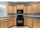 Well-lit kitchen featuring natural wood cabinetry, black appliances, and neutral countertops at 227 E Carob Dr, Chandler, AZ 85286