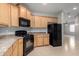 Modern kitchen with wood cabinets, black appliances, and tile flooring at 227 E Carob Dr, Chandler, AZ 85286