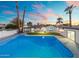 Inviting pool and outdoor space with palm trees at sunset in the backyard at 316 E El Camino Dr, Phoenix, AZ 85020