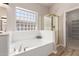 This bathroom features a tub with a glass block window and a walk in shower at 3765 E Del Rio St, Gilbert, AZ 85295