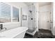 Bright bathroom featuring a soaking tub with black tile flooring and a glass-enclosed shower at 44560 W Copper Trl, Maricopa, AZ 85139