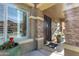 Inviting front porch with stone pillars, a secure iron door, and decorative potted plants at 44560 W Copper Trl, Maricopa, AZ 85139