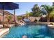 Backyard pool featuring a beautiful rock waterfall, lush greenery, and plenty of space for entertaining at 44560 W Copper Trl, Maricopa, AZ 85139
