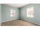 Cozy bedroom with two light-filled windows and neutral carpet at 501 W Romley Ave, Phoenix, AZ 85041